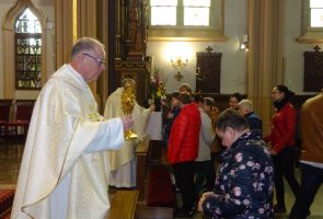 Ksiądz udzielający mieszkance sakramentu Komunii Świętej.