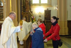 Ksiądz udzielający mieszkance sakramentu Komunii Świętej.