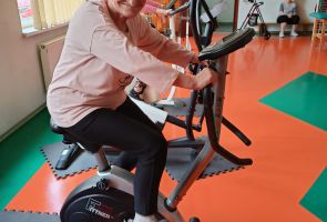 Mieszkanka ćwicząca na rowerze stacjonarnym w ramach zajęć rehabilitacyjnych.