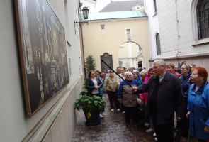 ksiądz wraz z grupą przy tablicy informacyjnej
